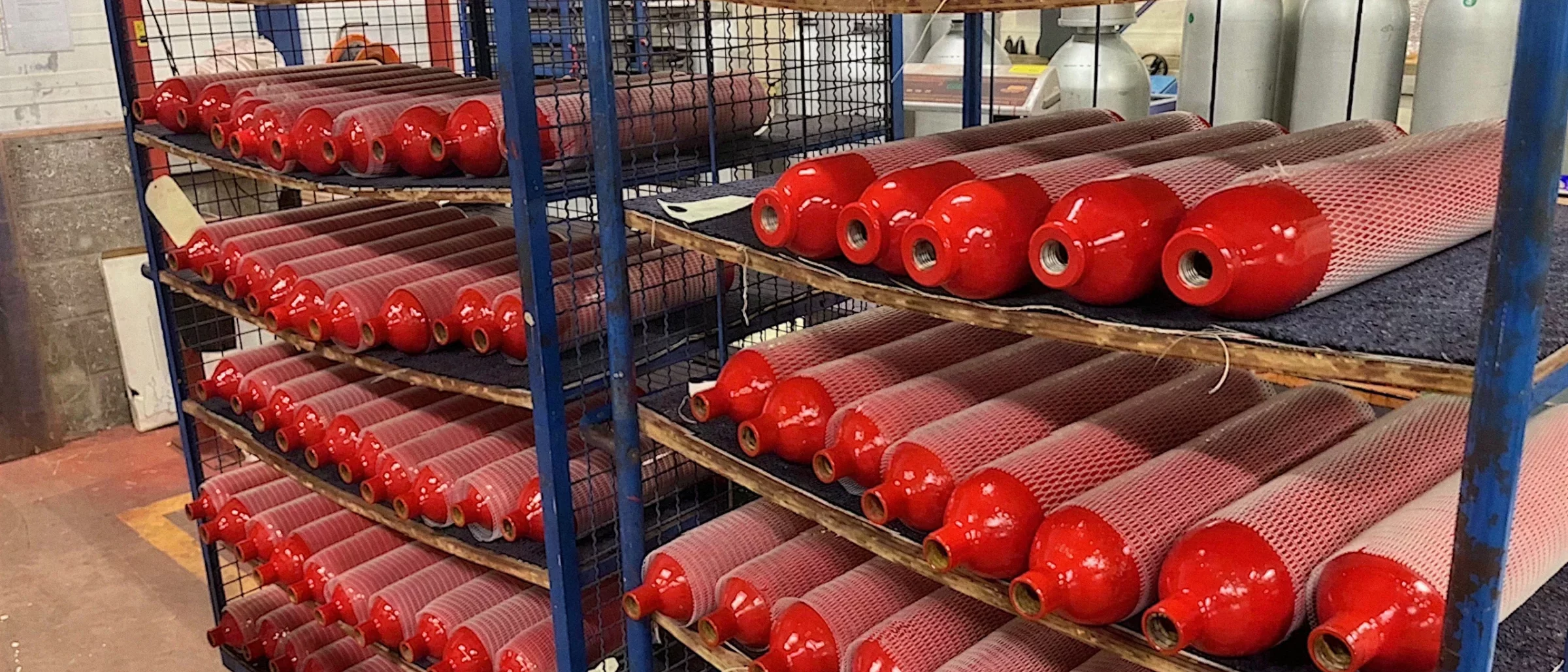 Corps de bouteilles repeints, protégés par un filet, sur les rayonnages de l'atelier