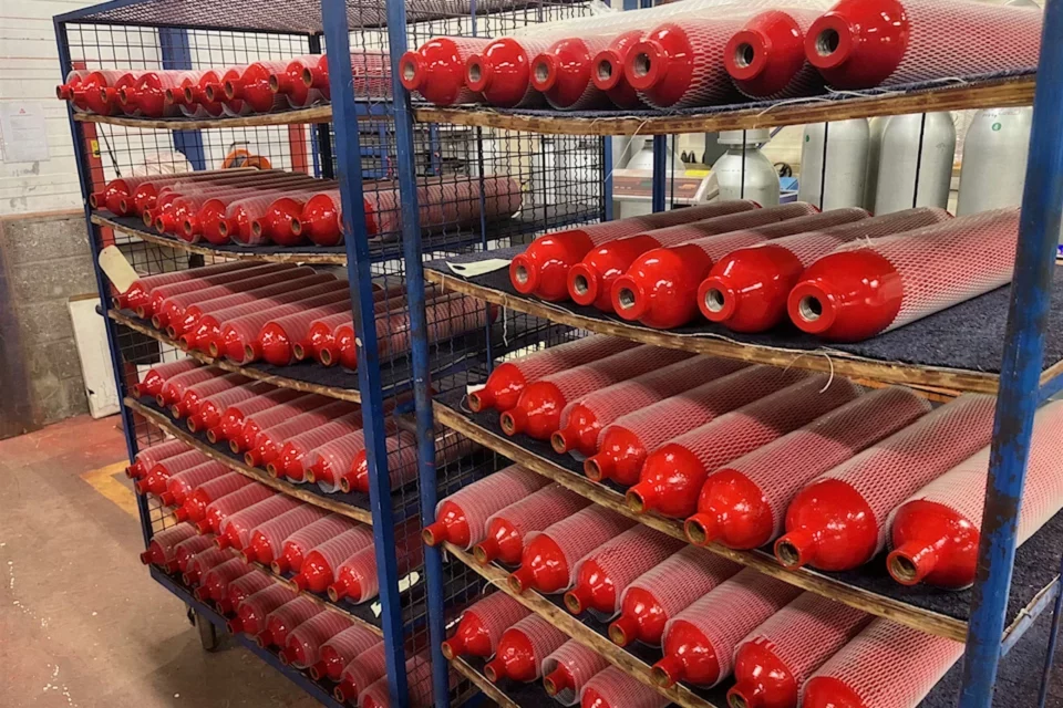 Corps de bouteilles repeints, protégés par un filet, sur les rayonnages de l'atelier